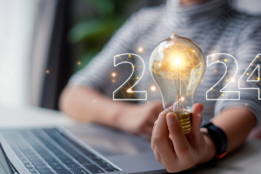 A Person Holding A Light Bulb With 2024 - Commercial HVAC Industry Trends - Springbank Mechanical Ontario Retail HVAC Company